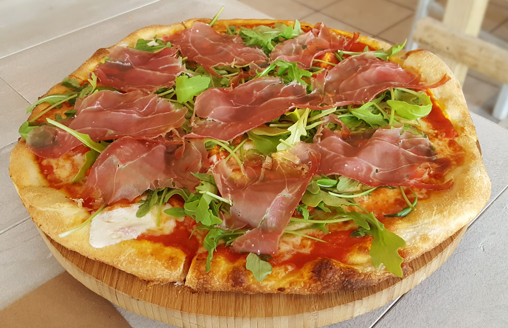 Italiana pizza at Il Faro topped with tomato sauce, Parma ham, cherry tomatoes, arugula and buffalo mozzarella.